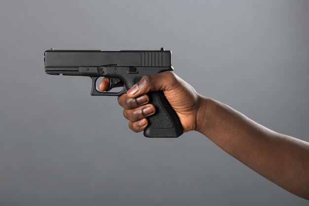 hand-black-man-holding-handgun-taking-aim-with-finger-trigger-grey-studio-background-conceptual-image-violence-crime-self-defence_126745-2976.jpg