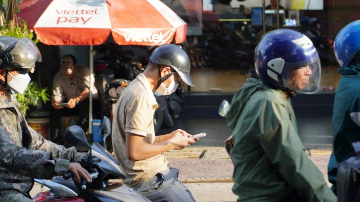 Người đàn ông dùng điện thoại khi chờ đèn ở đường Lý Thường Kiệt, TP Dĩ An,  Bình Dương - Ảnh: ĐỊNH DƯƠNG