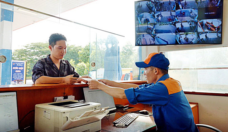 Nhân viên cửa hàng Petrolimex xuất hóa đơn giấy từ hệ thống hóa đơn điện tử cho khách hàng tại cửa hàng xăng dầu ở Hà Nội  - Ảnh: N.KH.