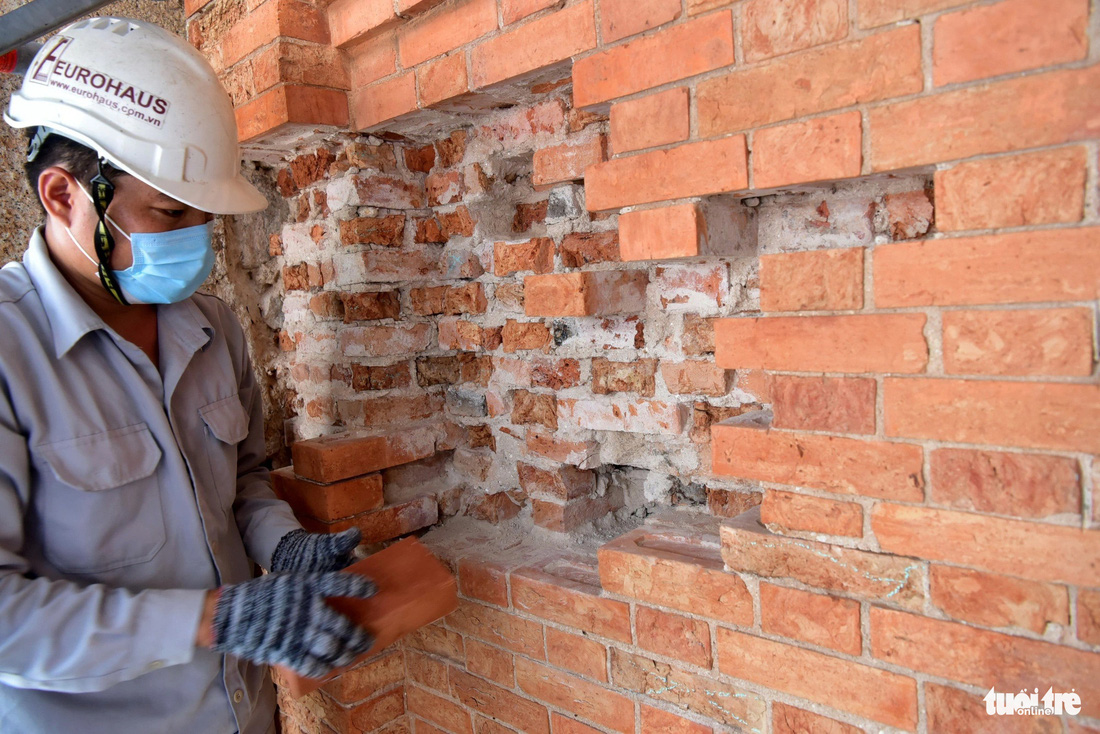 Kỹ thuật viên Đinh Vũ Quyền thay gạch sau khi đục, lấy những viên gạch hư mục ra khỏi bức tường mặt ngoài của nhà thờ - Ảnh: T.T.D.
