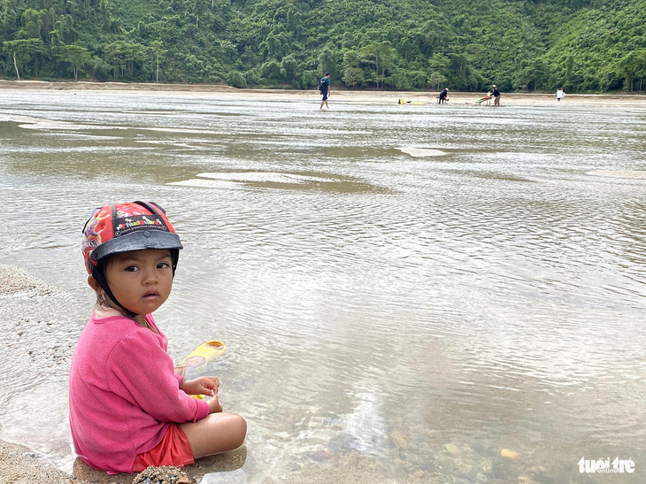 Em bé ngồi trên bờ chờ mẹ mót vàng kiếm miếng ăn trên sông Nước Mỹ - Ảnh: LÊ TRUNG