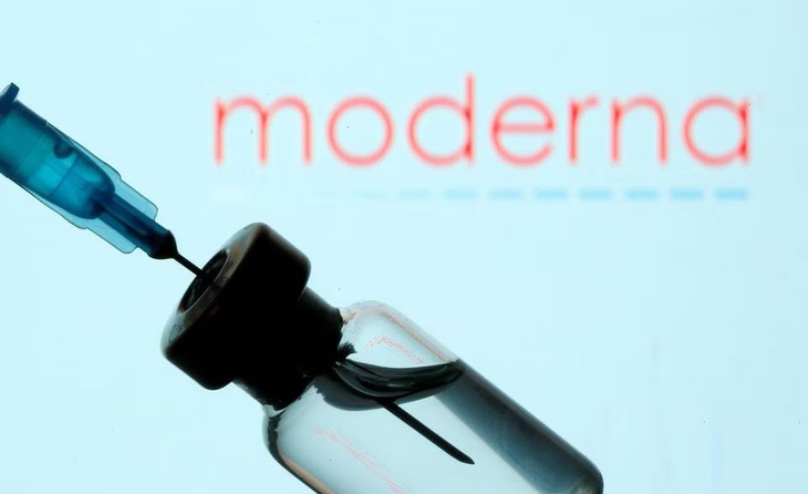 Một ống kim tiêm và lọ thuốc đặt trước logo của hãng Moderna - Ảnh: Reuters