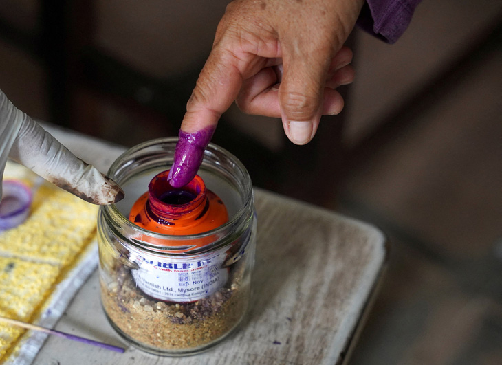 Cử tri Campuchia nhúng ngón tay vào lọ mực tím để đánh dấu đã bỏ phiếu vào hôm 23-7 - Ảnh: REUTERS