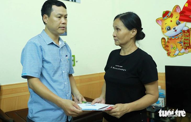 Đại diện báo Tuổi Trẻ trao cho bà Nguyễn Thu Thanh tiền hỗ trợ, chia sẻ nỗi mất mát lớn của bà và gia đình - Ảnh: DANH KHANG