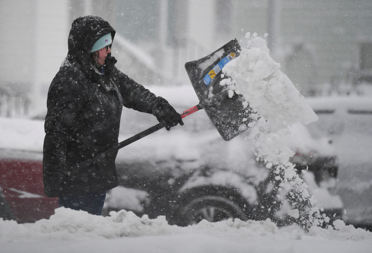 Người phụ nữ xúc lớp tuyết bao quanh xe ô tô của mình ở bang Massachusetts hôm 7-1, khi cơn bão mùa đông mang theo tuyết rơi dày đặc khắp vùng đông bắc Mỹ - Ảnh: REUTERS