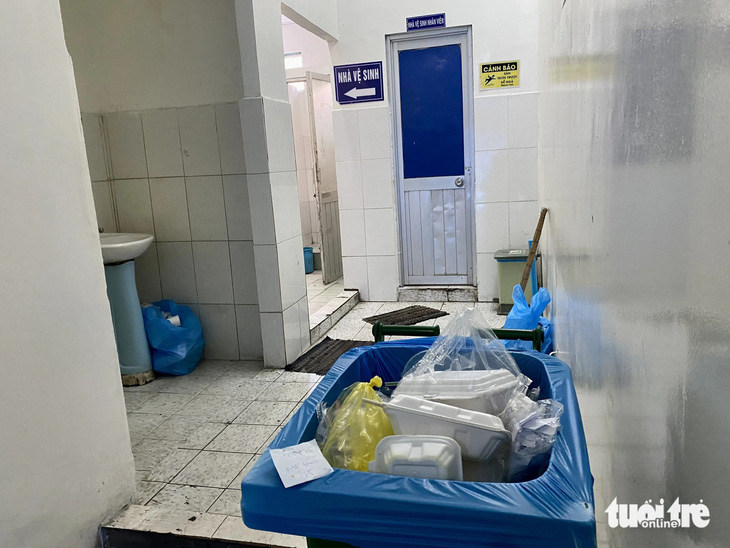Thùng rác chứa đầy rác được đặt ngay lối vào nhà vệ sinh tại khoa khám bệnh Bệnh viện Tâm thần (TP.HCM) trưa 16-1. Bên trong nhà vệ sinh bốc mùi hôi khó chịu, ô uế... - Ảnh: BÌNH NGHI