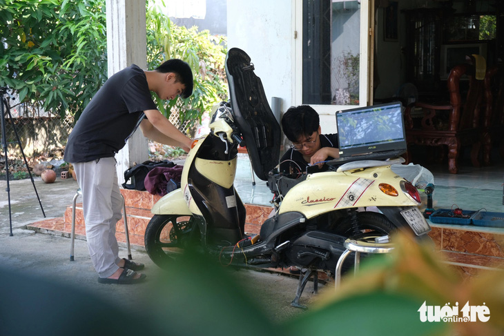Trần Nhật Thanh Huy và Huỳnh Nguyễn Anh Kiệt nghiên cứu trên xe máy của gia đình - Ảnh: NGỌC PHƯỢNG