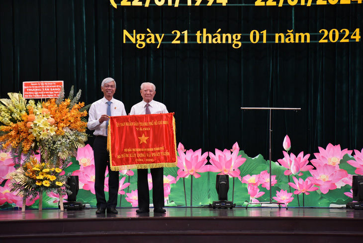 Ông Võ Văn Hoan - phó chủ tịch UBND TP.HCM - (bên trái) trao tặng cờ truyền thống UBND TP cho Hội Bảo trợ bệnh nhân nghèo TP.HCM trong buổi lễ kỷ niệm 30 năm thành lập hội - Ảnh: X.M.