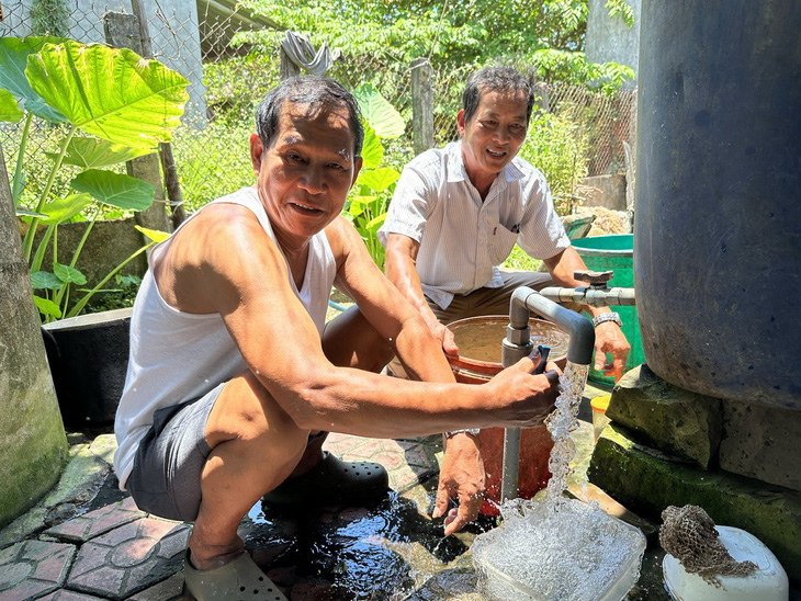 Ông Bảnh (phải) cùng người dân nở nụ cười hạnh phúc khi nước sinh hoạt ổn định từ lúc ông tiếp nhận và “hồi sinh” hai công trình cấp nước sinh hoạt “đắp chiếu” - Ảnh: TRẦN MAI