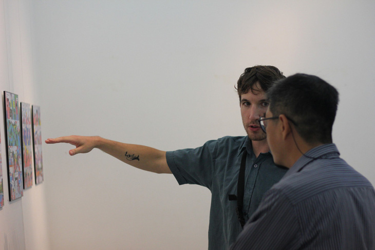 Họa sĩ người Pháp Jean Houzard (trái) giới thiệu với khách tham quan triển lãm về tác phẩm truyện tranh Non Stop Vinahouse của mình - Ảnh: MINH ĐĂNG