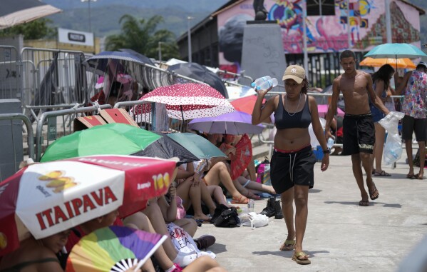 Street vendors sell bottled water to Taylor Swift fans amid a heat wave before her Eras Tour concert outside the Nilton Santos Olympic stadium in Rio de Janeiro, Brazil, Saturday, Nov. 18, 2023. A 23-year-old Taylor Swift fan died at the singer's Eras Tour concert in Rio de Janeiro Friday night, according to a statement from the show's organizers in Brazil. Both Swifties and politicians reacted to the news with outrage. While a cause of death for Ana Clara Benevides Machado has not been announced, fans complained they were not allowed to take water into Nilton Santos Olympic Stadium despite soaring temperatures. (AP Photo/Silvia Izquierdo)
