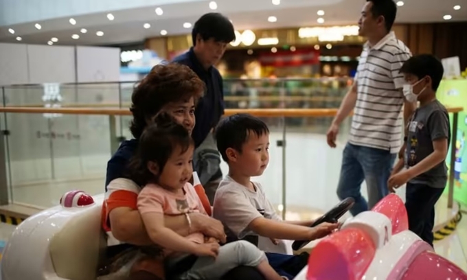 Người mẹ đưa con đi chơi tại một trung tâm thương mại ở thành phố Thượng Hải, Trung Quốc, hồi tháng 6/2021. Ảnh: Reuters.