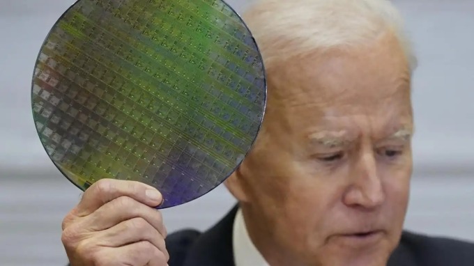 Tổng thống Mỹ Joe Biden cầm một tấm wafer silicon sản xuất chip trong hội nghị trực tuyến với các lãnh đạo doanh nghiệp chuỗi cung ứng chất bán dẫn hôm 12/4. Ảnh: AP.