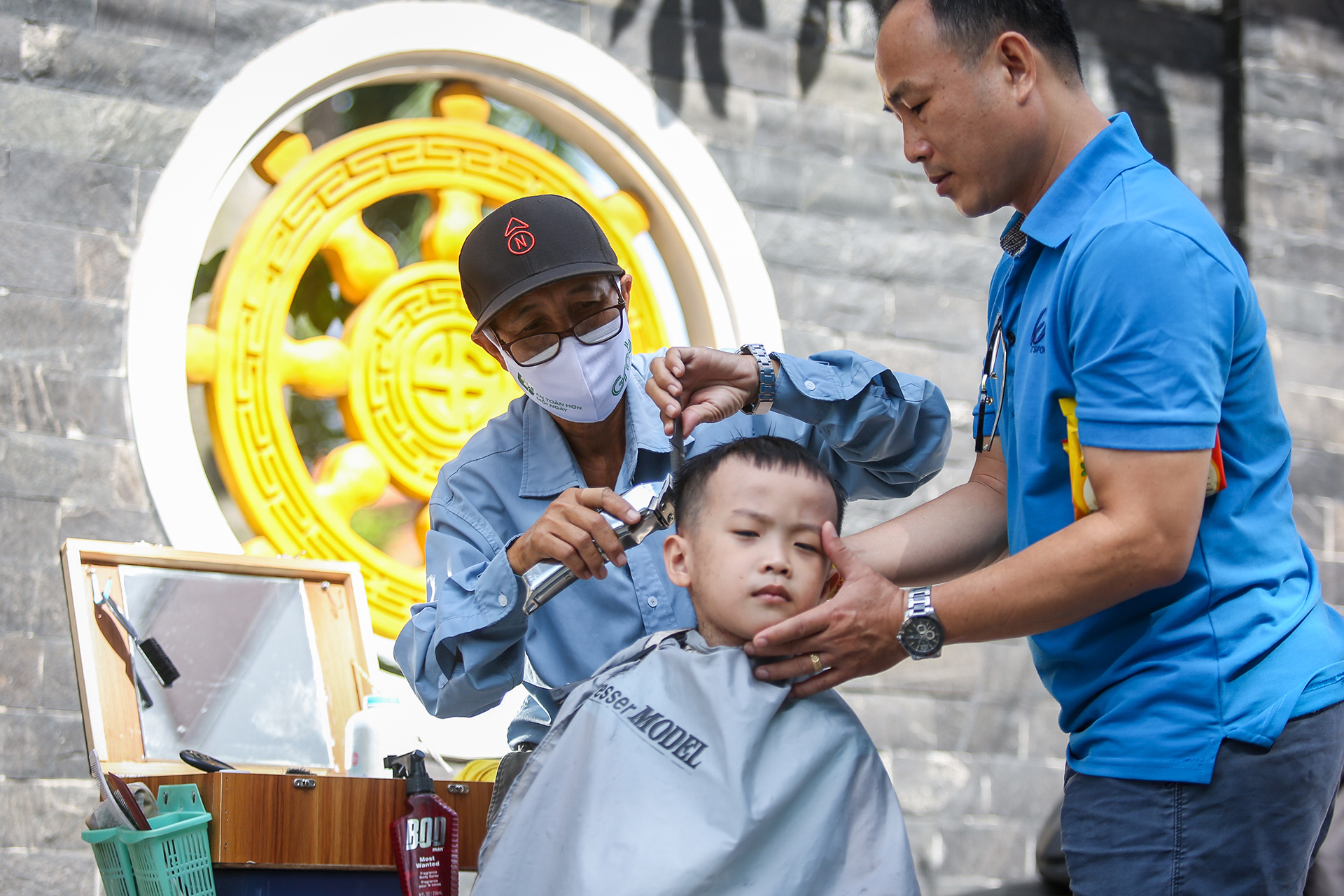 Ông Phấn cắt tóc miễn phí cho chon trai anh Trần Nguyên Sáng. Ảnh: NHẬT THỊNH